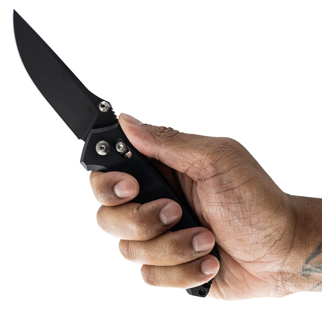 Hand holding a black folding knife against a white background