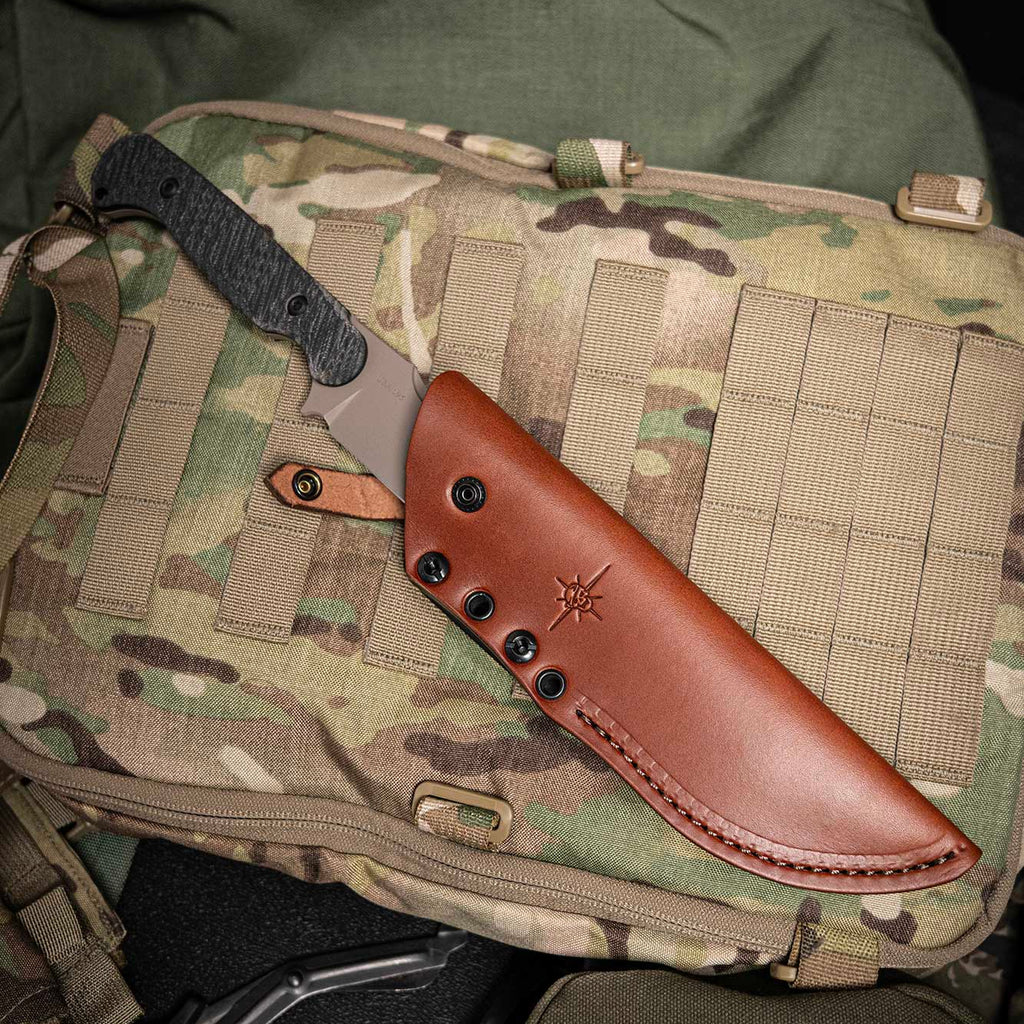 Knife with leather sheath on a camouflage bag