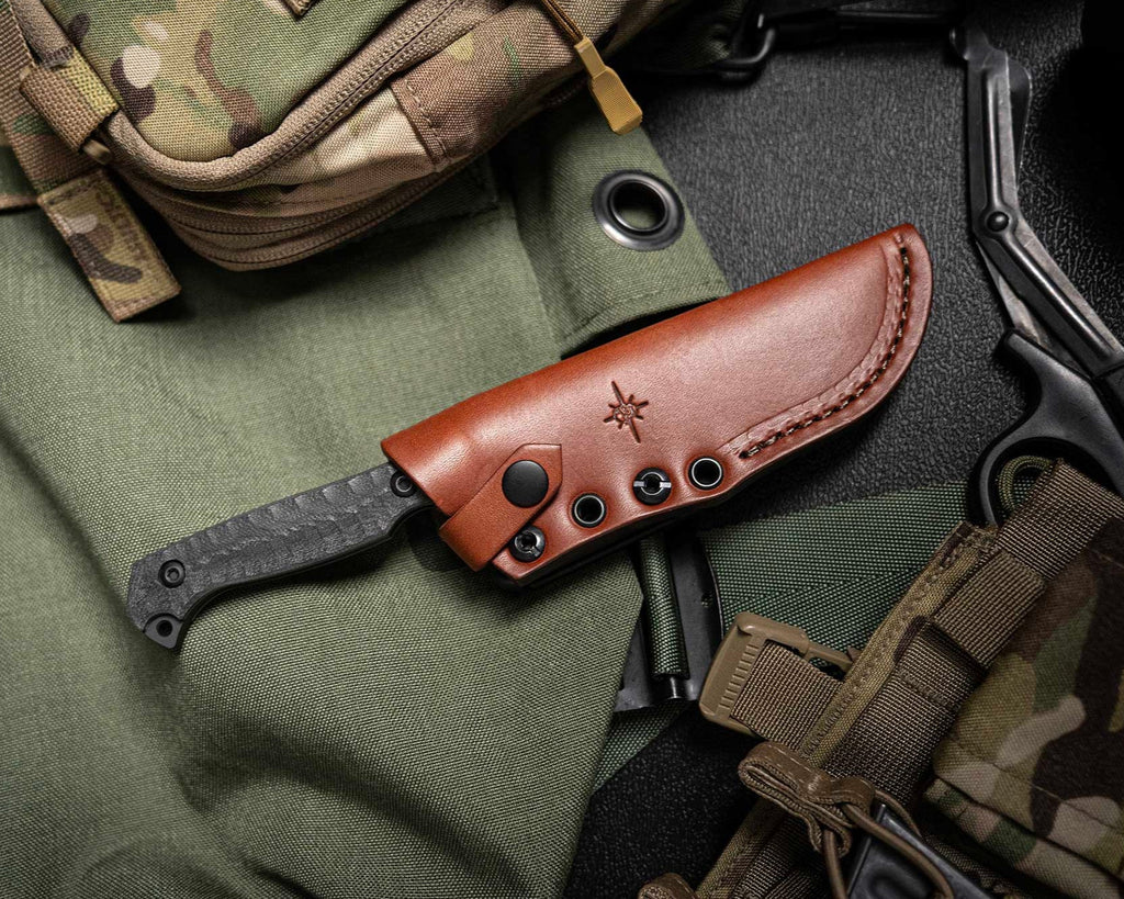 Knife with brown sheath on a green fabric background